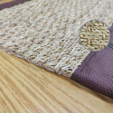 the corner of the SEAGRASS rug, with brown border, brown stitching and ecru natural mat color