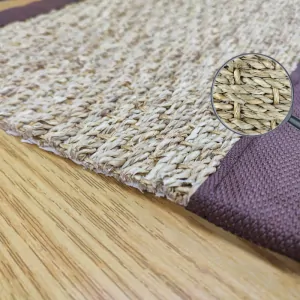 the corner of the SEAGRASS rug, with brown border, brown stitching and ecru natural mat color