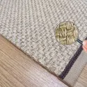 the corner of the rug, with beige border, brown stitching and ecru natural mat color