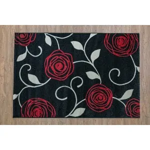 rug Color: black with a pattern of large red roses with gray leaves.