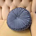 dark grey round pillow with pleats with velvet texture, on a black background