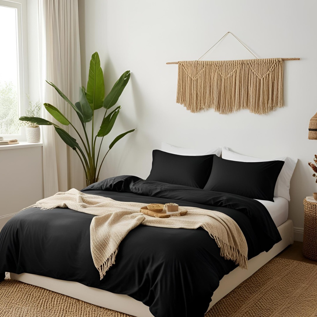 Bright summer boho bedroom with black sheets, beige throw, beige straw rug, and large indoor plant